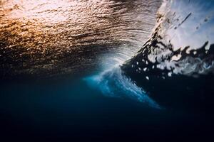 Wave crash in ocean with sunset or sunrise light. Underwater view of surfing wave photo