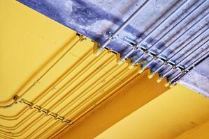 eléctrico metal tubo en crudo y amarillo hormigón techo. foto