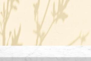 Minimal white marble table with tree shadow on beige concrete wall texture background photo