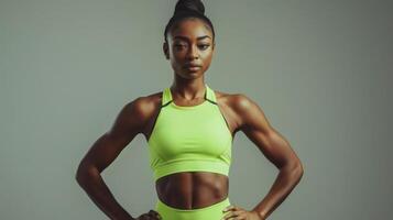 A woman in a neon yellow active tank and shorts stands with hands on hips photo