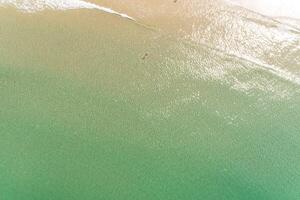 directamente encima aéreo zumbido ver de dos personas en turquesa agua en el apuntalar de un playa disfrutando el verano foto