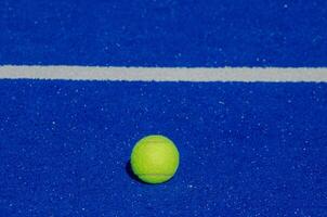 azul paleta tenis corte, un solitario pelota cerca a el base foto
