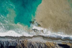 Aerial view of sea surface with waves, dirty water and coastline photo