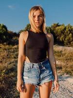 Portrait of young blonde woman in shorts posing outdoor and sunset light. photo