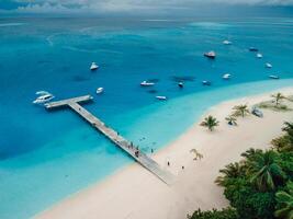 aéreo zumbido ver de paraíso Maldivas tropical playa con muelle y velocidad barcos en isla. verano y viaje vacaciones concepto. foto