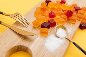 azucarado Fruta jalea en un de madera plato con cuchara, tenedor y cuchillo foto