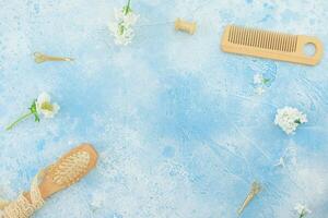 Hair dresser composition with hairbrush, tassel and white flowers on blue. Flat lay, top view photo