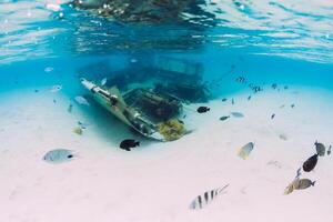 Ocean with wreck of boat on sandy bottom and tropical fish underwater in Mauritius photo