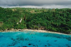 Drone view of cliff coastline with turquoise ocean and beach in Bali photo