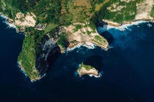 Coastline with rocky cliffs and ocean in Nusa Penida. Aerial view of island photo