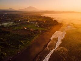 Aerial view of beach with Agung mountain, warm sunrise or sunset tones and ocean in Bali photo