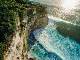 Aerial view of coastline with cliffs, ocean with waves at sunset photo