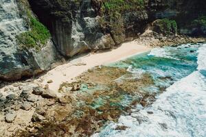 Hidden beach with rocks and ocean with waves in Bali. Aerial view. photo