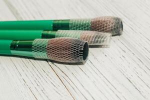 Green makeup brushes on a wooden table. photo