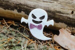 Toy ghost made of felt in the forest, Halloween decor photo