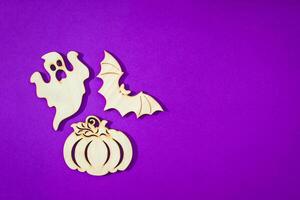 Wooden toy bat, ghost, pumpkin on purple background Halloween concept photo