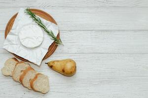 Camembert cheese with pear and rosemary sprig on the table. photo