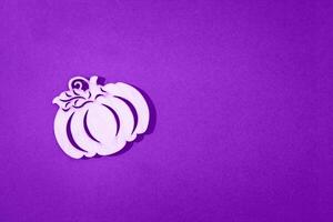 Wooden toy pumpkin on purple background Halloween concept photo