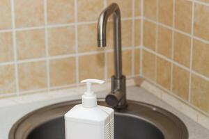 Kitchen sink with faucet and gloves for cleaning and detergent. photo
