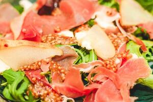 Salad with herbs, arugula, prosciutto, cheese, green olives and nuts. photo