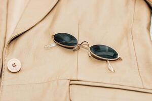 Gold-rimmed sunglasses on the texture of a brown leather jacket, genuine soft leather photo