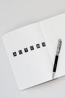 Filling in the diary, writing Autumn in a notebook in a dot photo