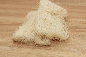 Funchoza rice glass noodles on a wooden board. photo