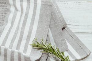 Fresh green sprig of rosemary seasoning on table with kitchen towel. photo