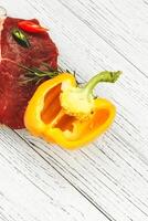 A piece of premium meat, striploin steak on a wooden table with pepper photo