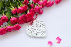 decorativo blanco corazón hecho de vides, San Valentín día en el antecedentes de un ramo de flores de rosas. foto