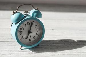 Blue alarm clock on a wooden table, time concept photo