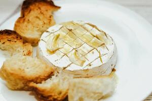 White baguette cut into pieces with olive oil and Camembert cheese on the table. photo