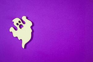 Wooden toy ghost on purple background Halloween concept photo