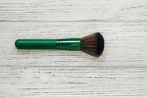 Green makeup brushes on a wooden table. photo