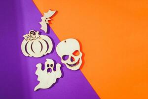 Wooden toy skull, bats, pumpkin on orange and purple background Halloween concept photo