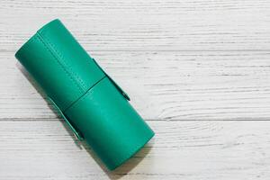 Green case with make-up bones on a wooden table. photo