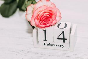 Pink tea rose with heart shaped pink mousse cake and February 14 calendar. photo