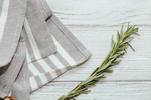 Fresh green sprig of rosemary seasoning on table with kitchen towel. photo