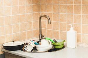 A pile of dirty dishes, cups, plates in the sink. photo