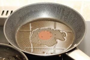 a frying pan with oil is heated on the stove, dirty fat photo