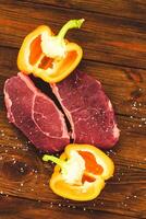 A piece of premium meat, striploin steak on a wooden table with pepper photo