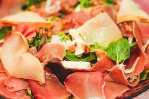 Salad with herbs, arugula, prosciutto, cheese, green olives and nuts. photo
