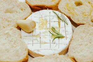 White baguette cut into pieces with olive oil and Camembert cheese on the table. photo