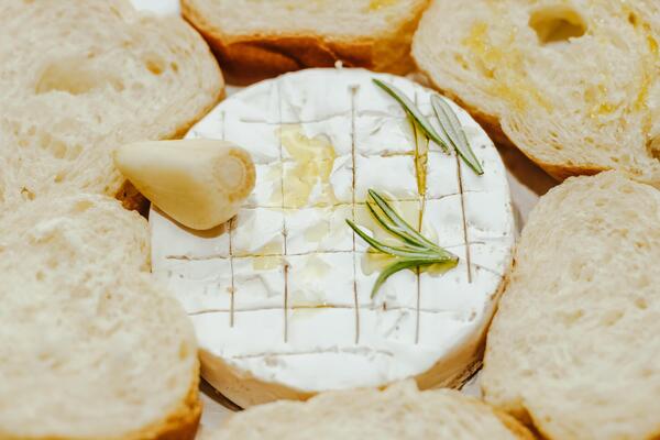 White baguette cut into pieces with olive oil and Camembert cheese on the table.