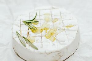 Round cheese in camembert mold with a sprig of rosemary and olive oil on the table. photo