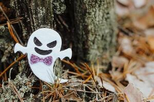 Toy ghost made of felt in the forest, Halloween decor photo