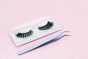 Artificial false fluffy eyelashes with tweezers. photo