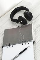 Notepad diary with pen and headphones on the desktop photo