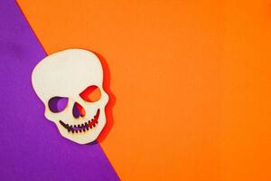Wooden skull toy on orange and purple background Halloween concept photo