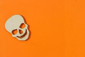 Wooden skull toy on orange background Halloween concept photo